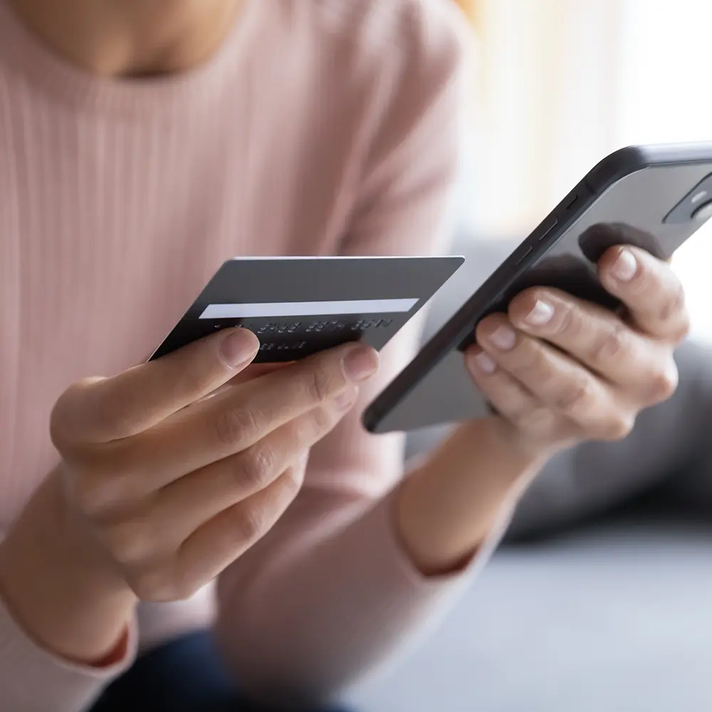 woman holding credit card and phone